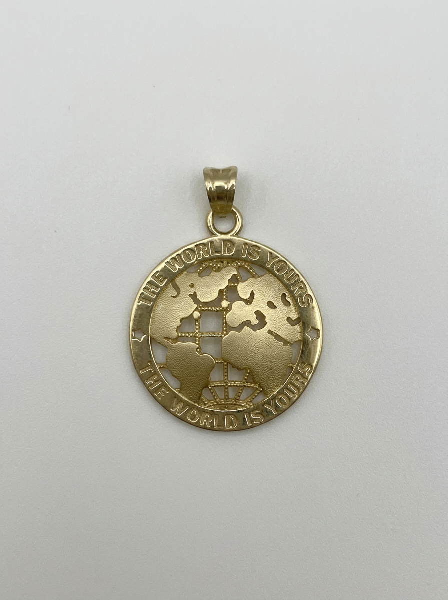 A gold pendant featuring a cutout globe design with continents and the engraved text 'THE WORLD IS YOURS.