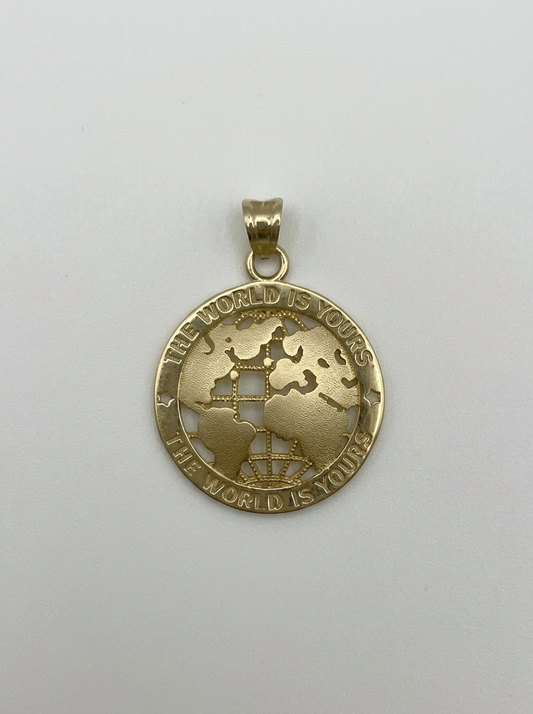 A gold pendant featuring a cutout globe design with continents and the engraved text 'THE WORLD IS YOURS.