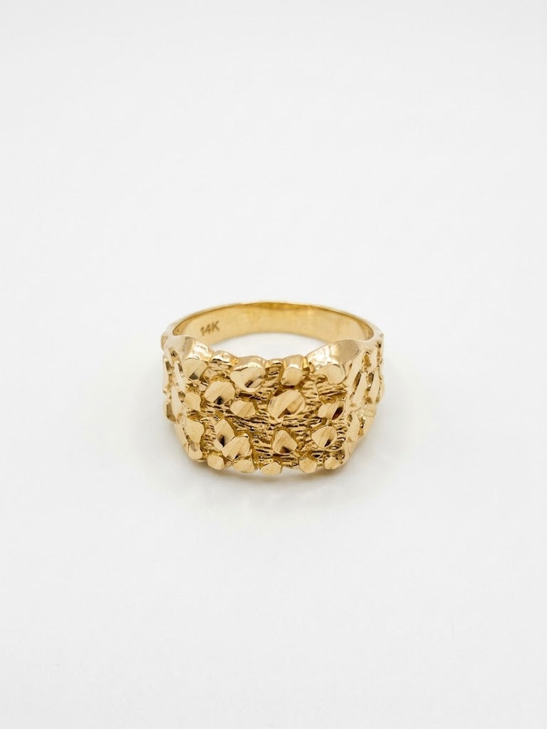 A textured gold ring with a wide, chunky band featuring a raised, organic, pebble-like pattern, photographed on a clean white background.